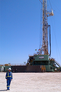 Julia McElgunn, P.Geo., stands in front of an oil derek.