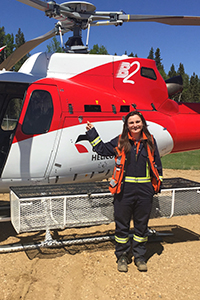 Nancy Manchak, P.Eng., stands in front of a red helicopter, ready to take a flight to her work.