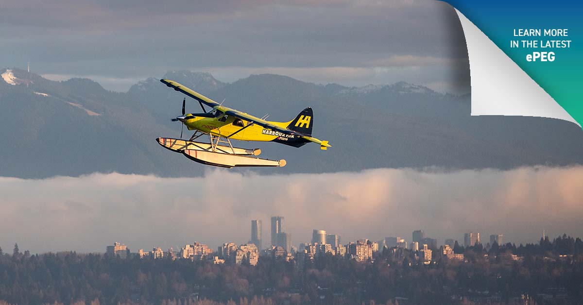 An electric float plane soars in the cloud-riddled sky, framed by the mountains of Fraser, B.C.